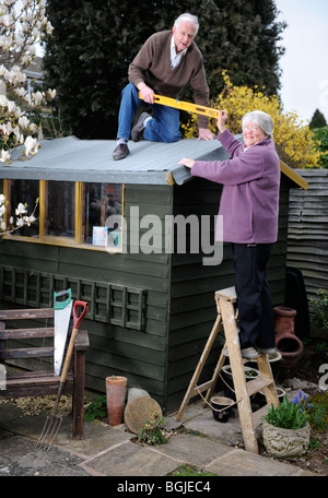 A retired man re-felting a shed roof UK Stock Photo 